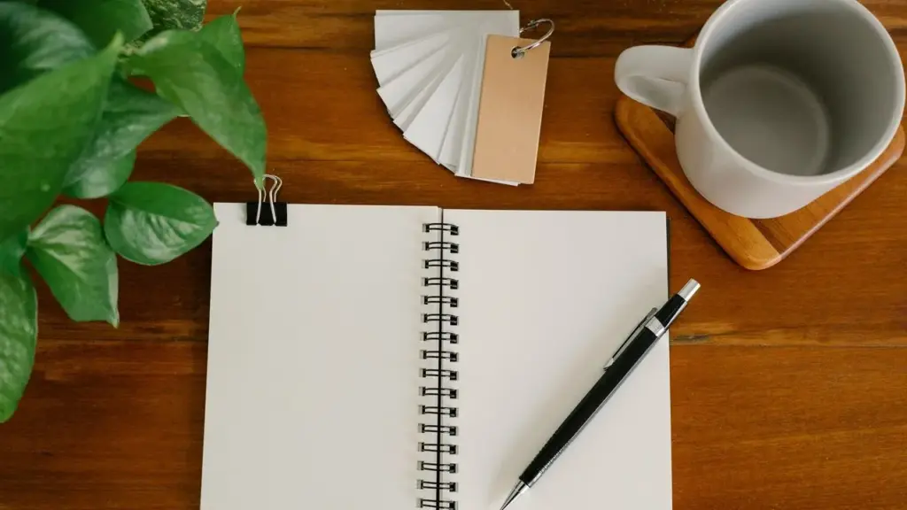 Redaktionsschreibtisch mit Notizbuch, Stift und Pflanze
