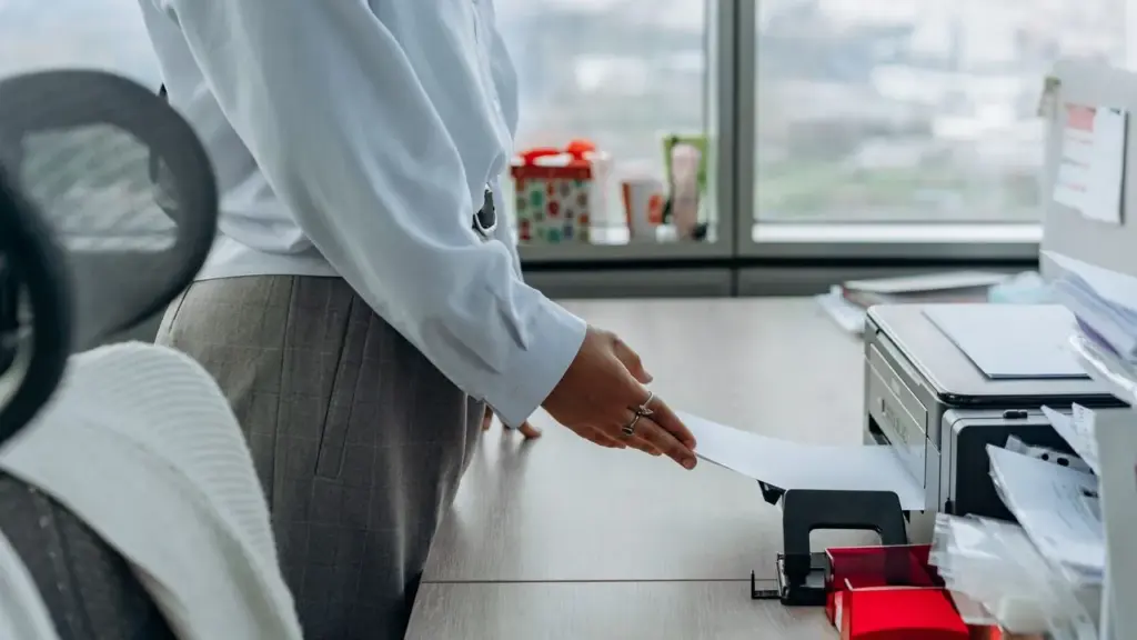 Person legt Papier in einen Drucker im Büro