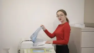Büroangestellte nimmt ein Blatt aus dem Drucker am Arbeitsplatz