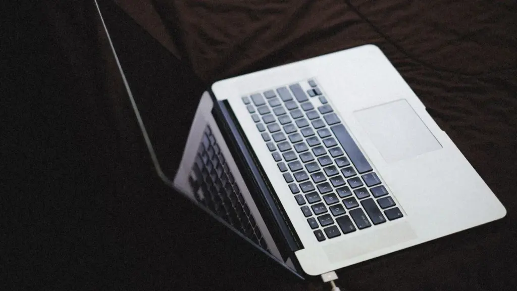 Laptop mit angeschlossenem Ladekabel auf dunklem Untergrund