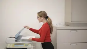 Multifunktionsdrucker druckt Fotos, eine Hand hält einen Stift