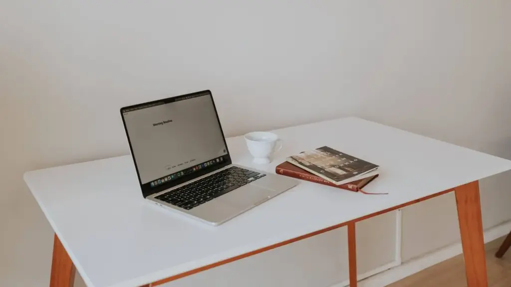 Laptop mit geöffnetem Bildschirm und Kaffeetasse auf einem weißen Schreibtisch